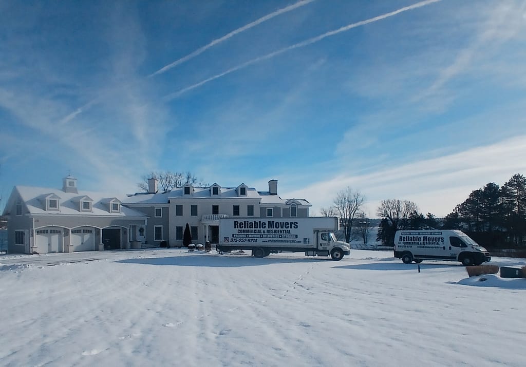 Reliable Movers crew loading household items onto a moving truck during a snowy winter day in upstate New York